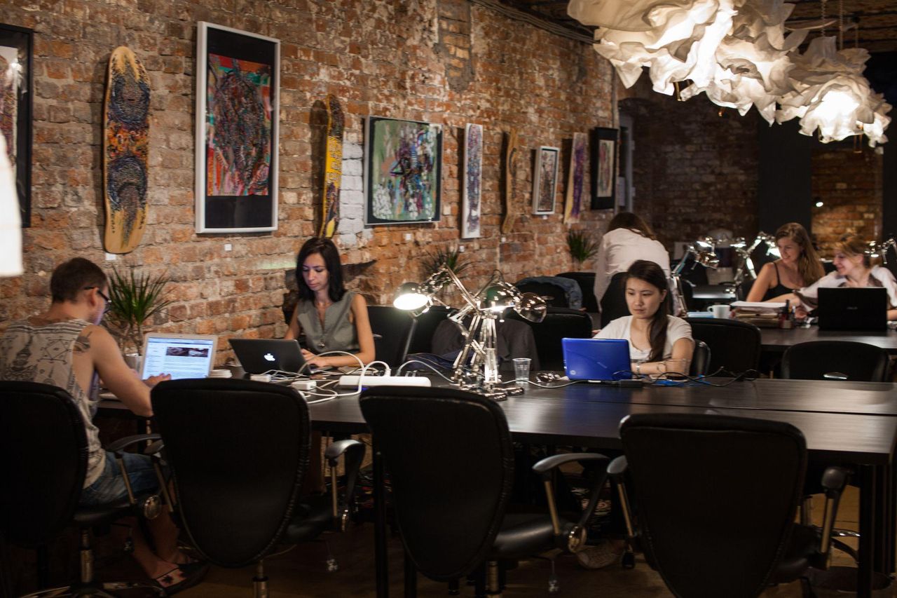 The co-working room: brick walls hung with paintings and skateboard decks, founders working along a long black table