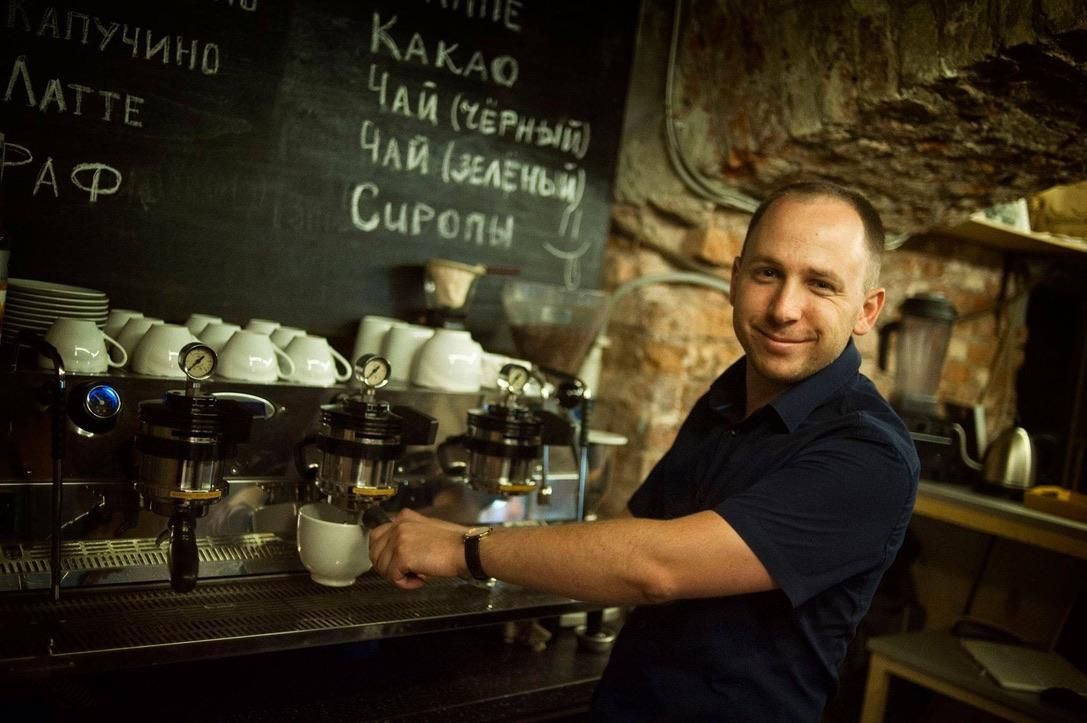 The barista at the La Marzocco Strada, under a chalkboard coffee menu